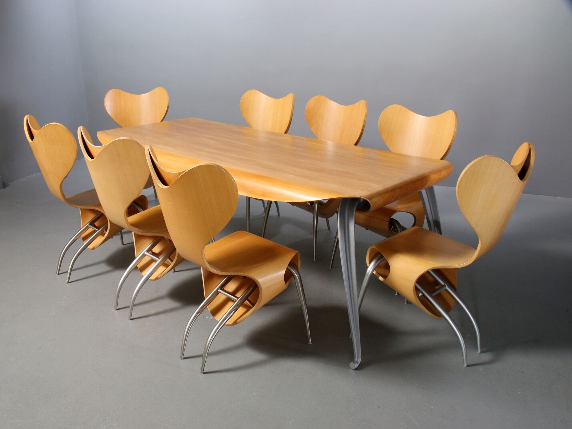 8 Empty Chairs and Fly Ply table in birch with a cast aluminum frame.